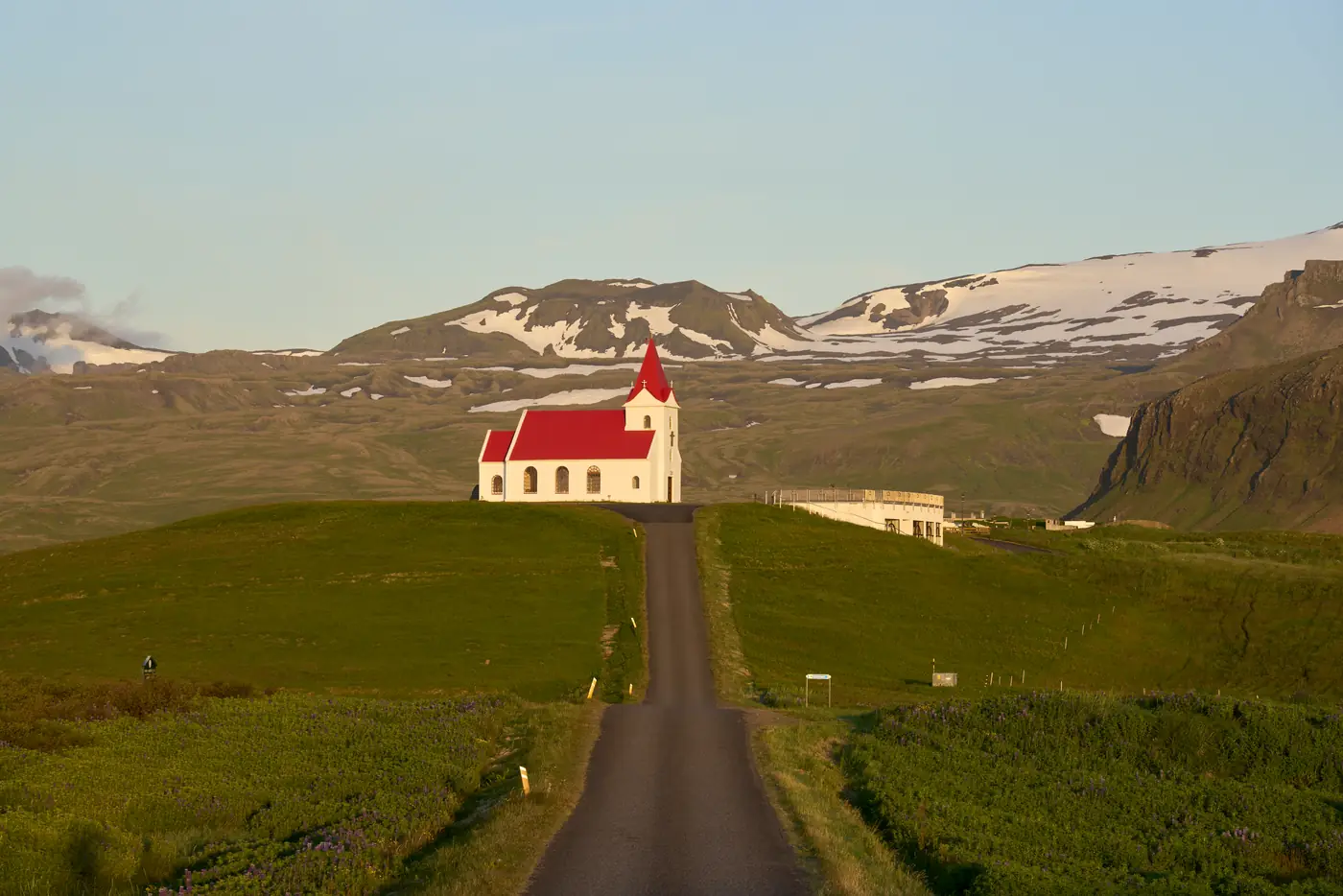 A road past a farm with a red roof