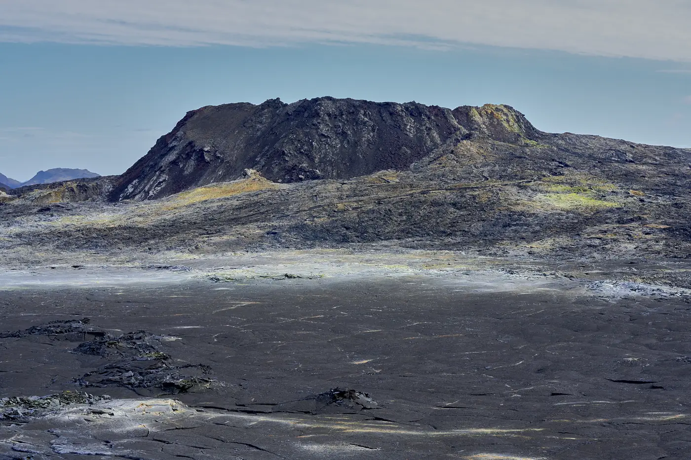 A dark volcanic mountain above a lava field