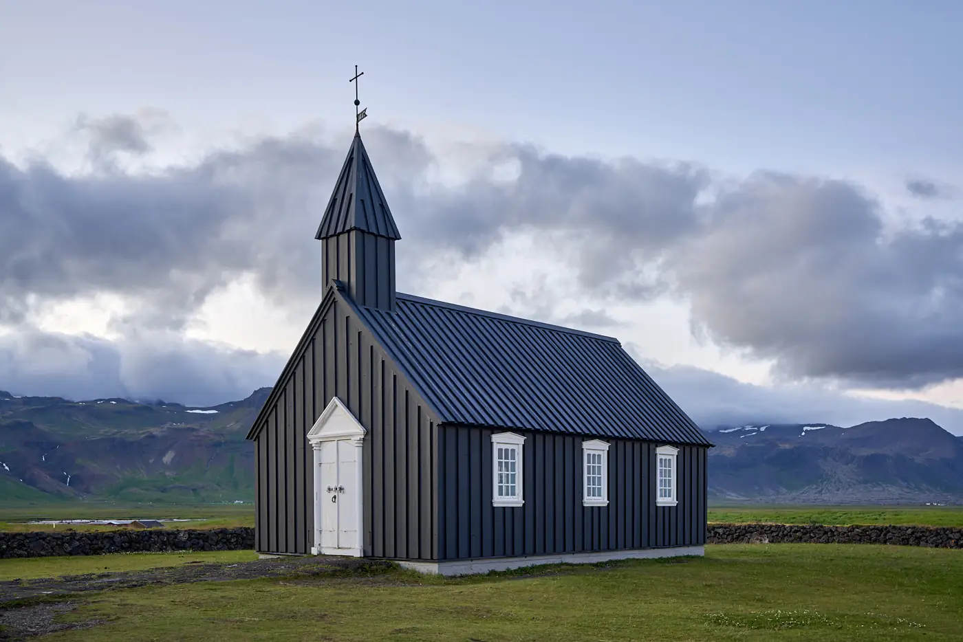 Eine schwarze Holzkirche in offener Landschaft