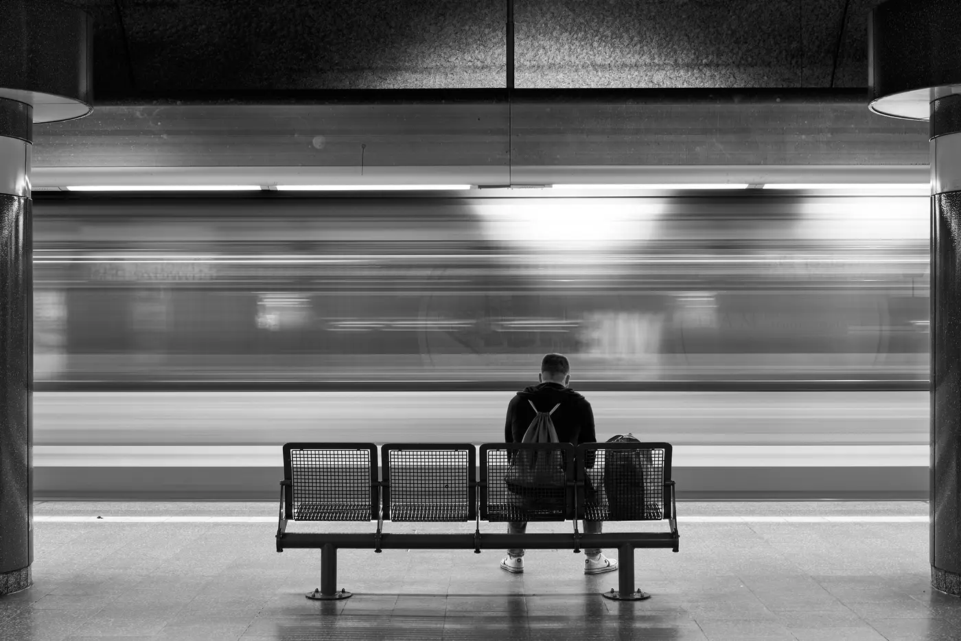 A lone figure on a platform bench, black and white